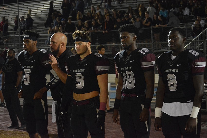 Quarterback Arthur Brantley IV gets coin toss instructions from coach Josh Smithers as he, junior Julian Lowenstein, senior Stephon Turner and junior Johnny Dawson wait to walk to midfield.