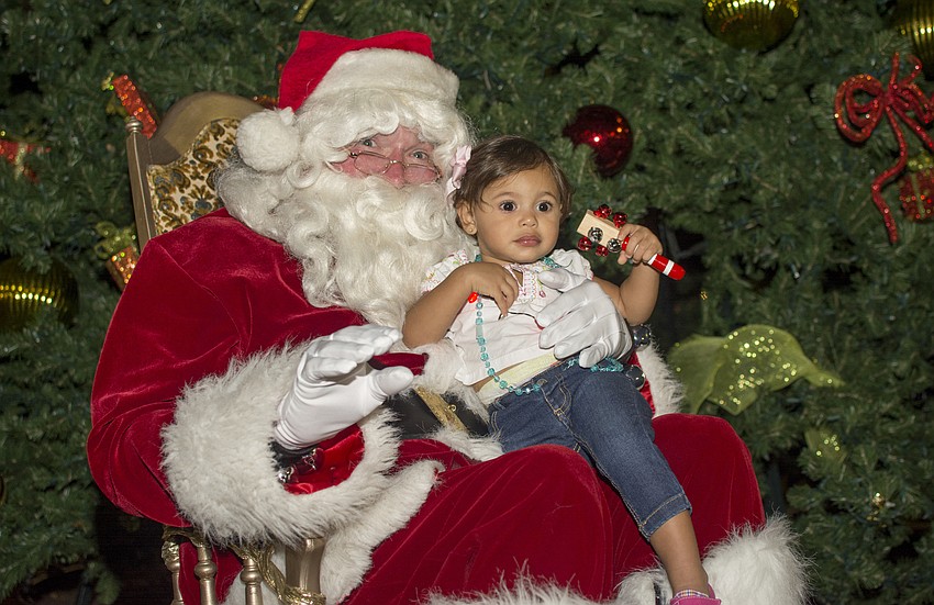 Sophia Rios poses with Santa Claus in front of the tree in Five Points Park.