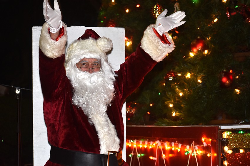 Santa Claus celebrates flipping the switch to turn on the Christmas tree lights.