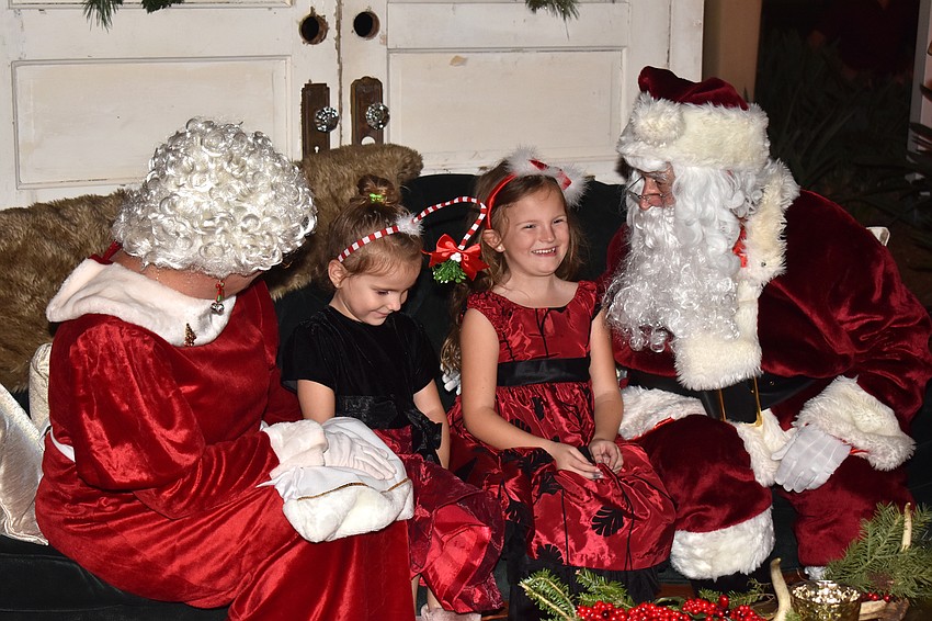 Nichole and Brooke Messenger laugh with Santa and Mrs. Claus.