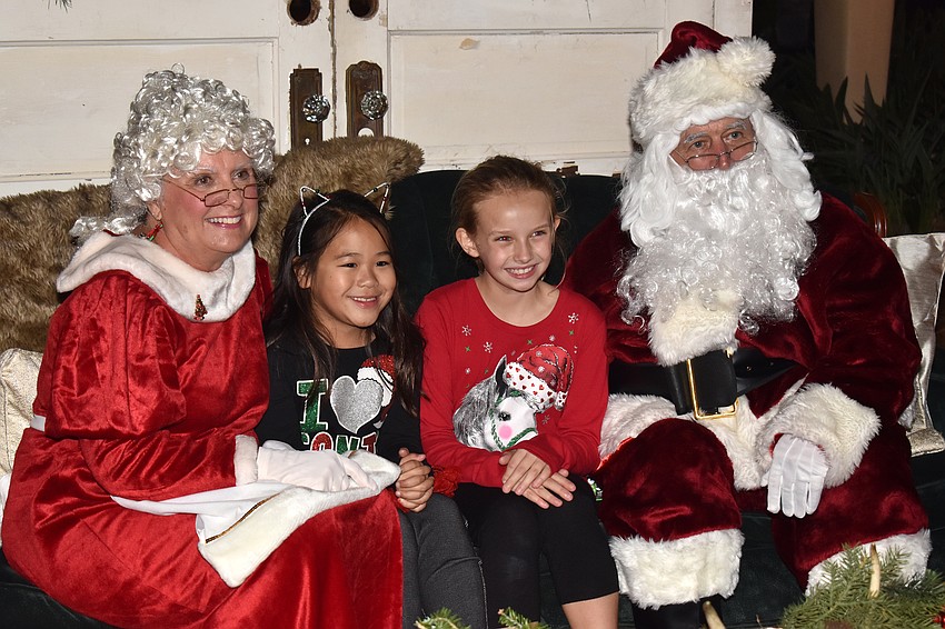 Lana Tran and Colleen Putnam pose with Santa and Mrs. Claus.