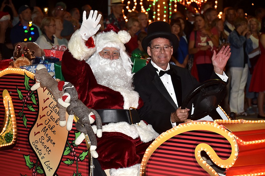 Santa Claus and his chauffeur pose in the sleigh after lighting the tree.