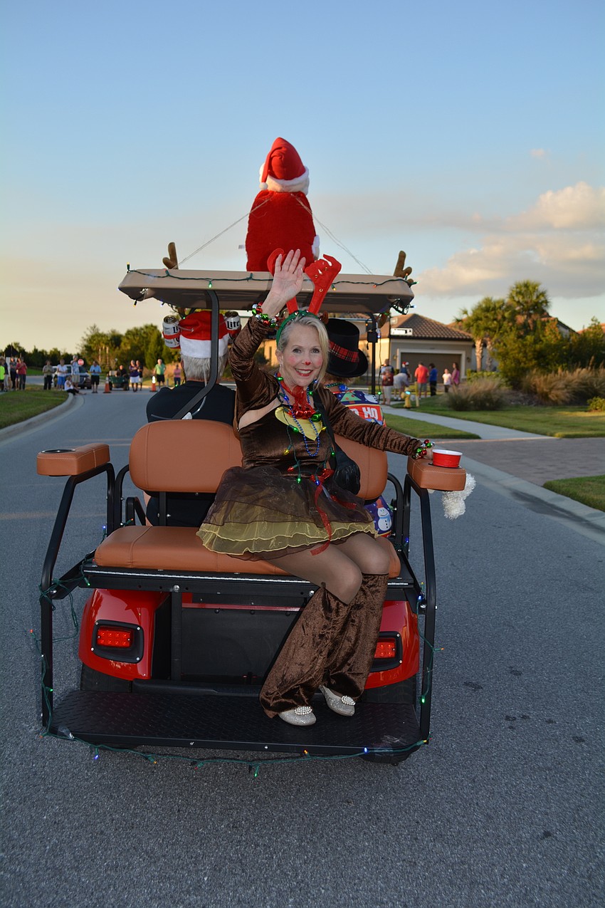 Nancy Groff waved from the back of the golf cart of Jack and Joyce North.