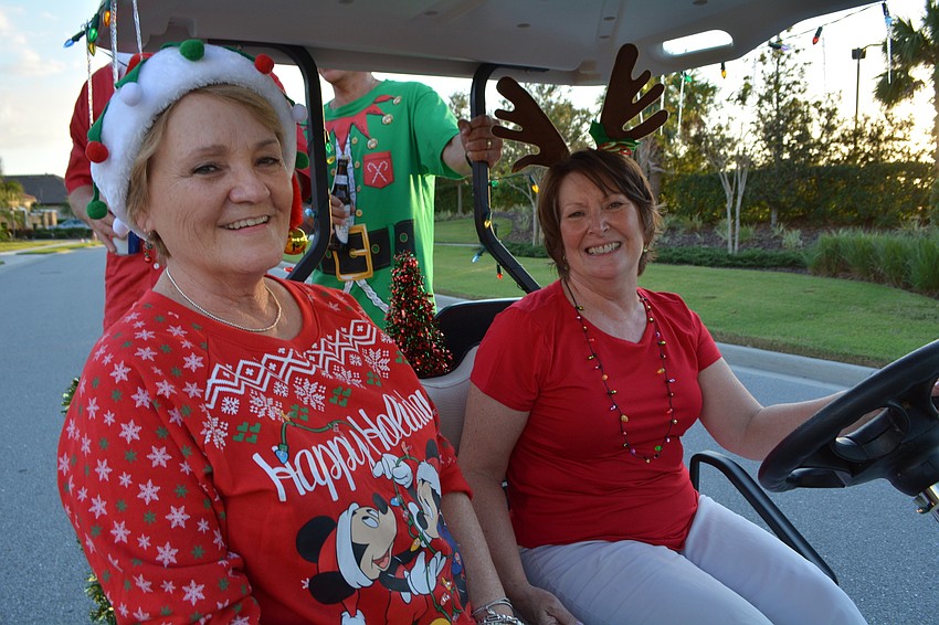 Nancy Bombino and Kathy Arentz are all smiles as their husbands, Mike Bombino and Denny Arentz, wave from the back of the golf cart.