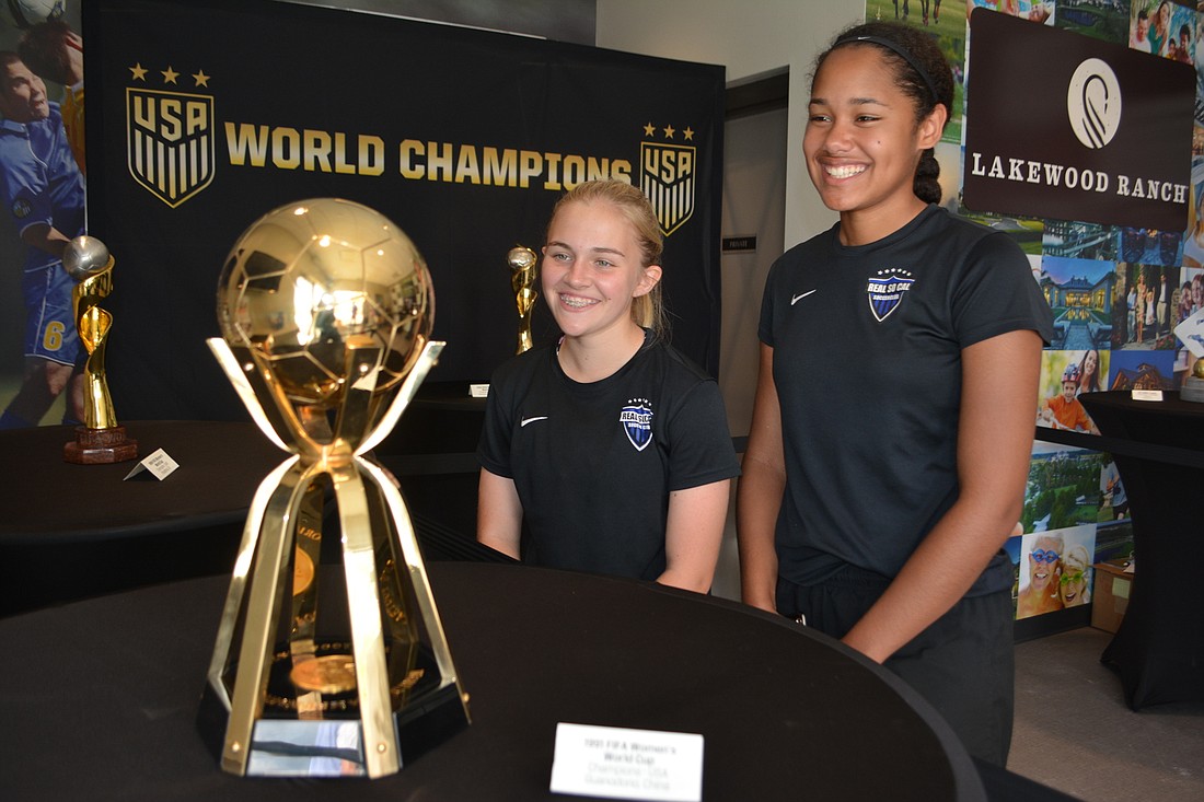 Samantha Castro and Savana Durr, who play for the Real So Cal club team, look at the 1991 Women&#39;s World Cup trophy on Thursday at Premier Sports Campus in Lakewood Ranch.