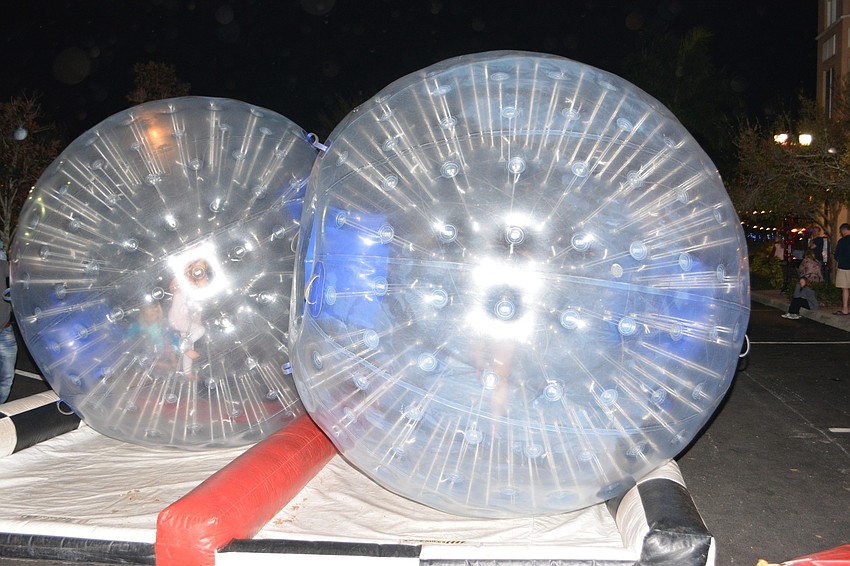 A long line of children waited to try out the big inflatable balls. They climbed inside and rolled down the street.