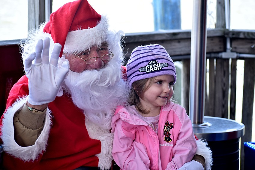 Presley Scott smiles while her parents take her picture with Santa Claus.