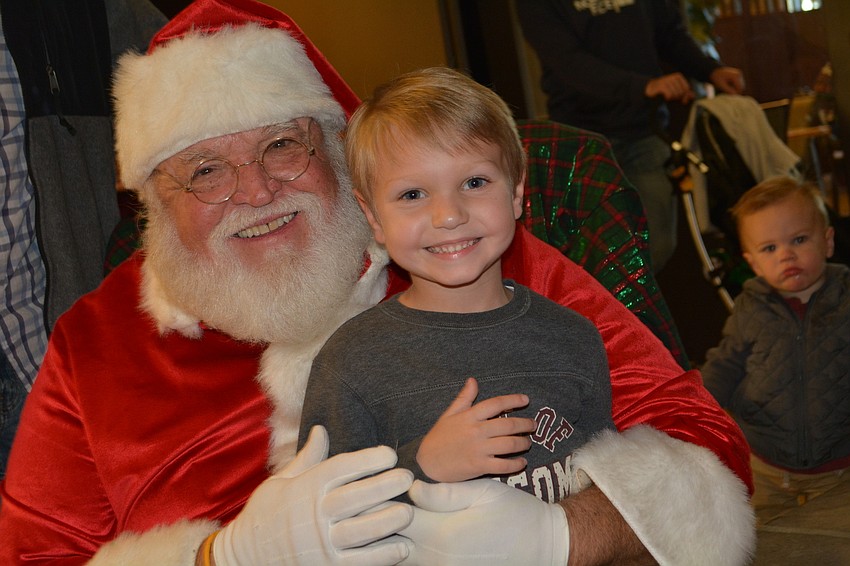 Santa (Ron Lee), poses with Parker Belew, 5, who is all smiles on Santa's lap.