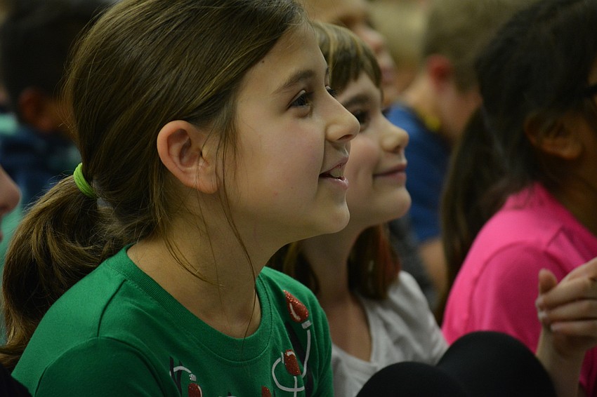 Third graders Gaby Papageorgiou and Emma Cappelluti smile as a first-graders start a song they know.