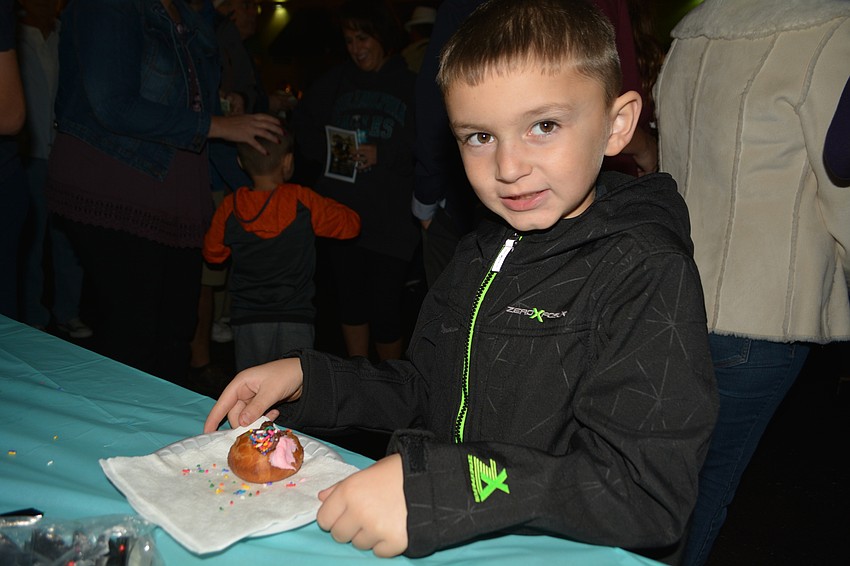 Six-year-old Connor Van Calligan, of Lakewood Ranch, decorates a doughnut with chocolate frosting and sprinkles.