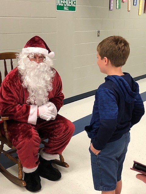 Damien Lopez hands a letter to Santa during the Cookies with Santa event. Courtesy photo.