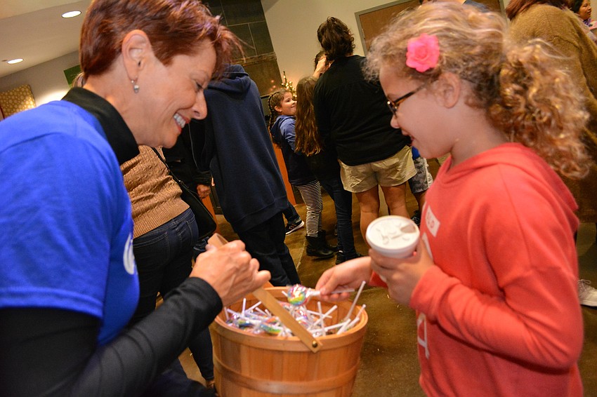 Bayside volunteer Debra Pedrow gives a lollipop to Sophia Morales, 7, of Parrish.