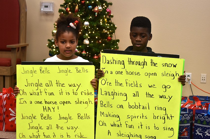 Students hold signs during a sing along to greet Santa Claus.