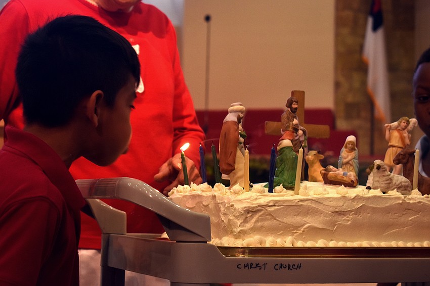 Students blow out candles on a birthday cake for Jesus.
