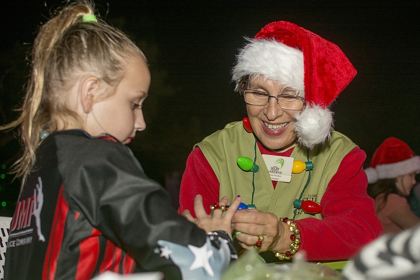 Maria Puszkar smiles while helping Lights and Bloom guests at one of the craft tables.