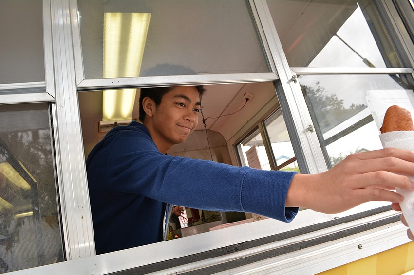 Heritage Harbour resident Elijah Gelongo, a junior at Southeast High School, serves corn dogs to the public.