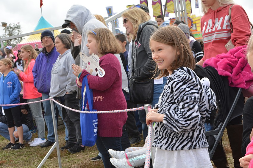 Caroline Grindstaff, 5, visiting from Lakeland, cheers for the pig races.