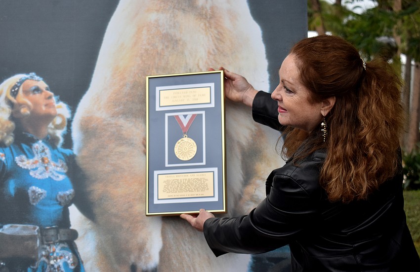 Sherry Powell holds up Ursula Boettcher plaque to a photo of Boettcher and the polar bear, Alaska.