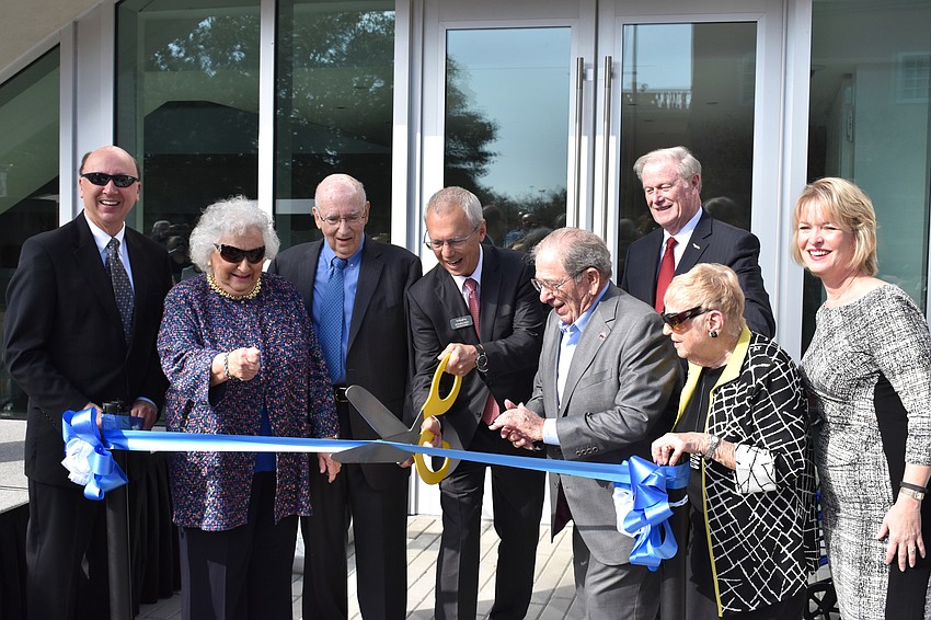 Mark Pritchett, Nancy and Phil Kotler, Steven High, Warren Coville, John Thraser, Margot Coville and Veronica Brady celebrate the ribbon cutting.