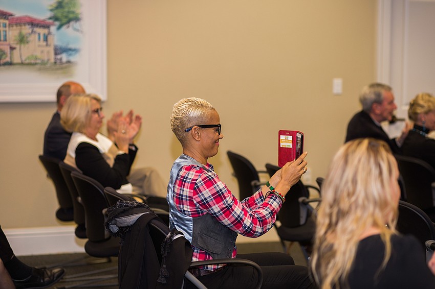 Brook Bello takes a video of Felicity and Chris Hill receiving More Too Life's check.