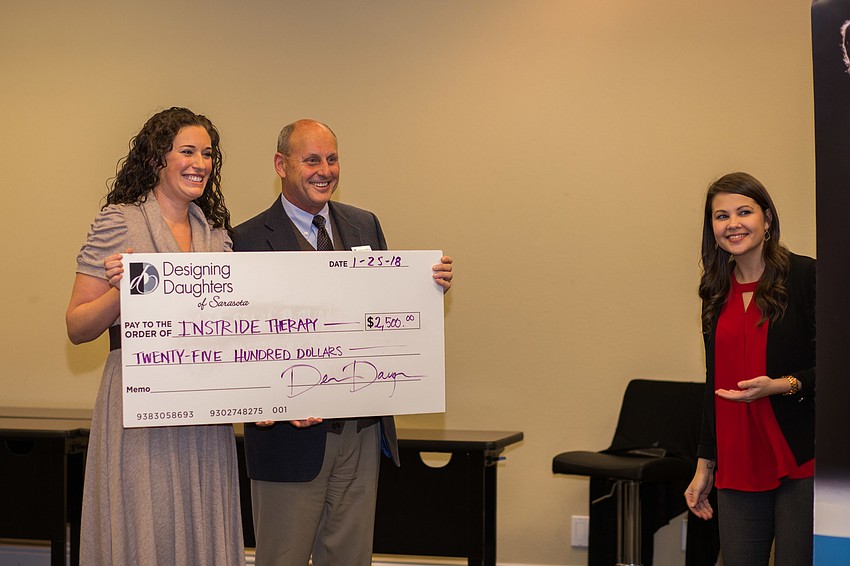 Designing Daughters President Elli Baldwin and Instride Therapy CEO Dana Johnston smile for a photo with Instride Therapy's check.