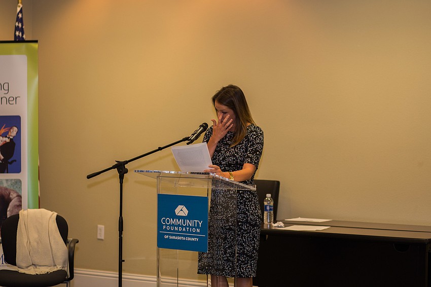 Jen Rust becomes teary-eyed as she reads Mothers Helping Mother's story before granting them with a $5,000 check.