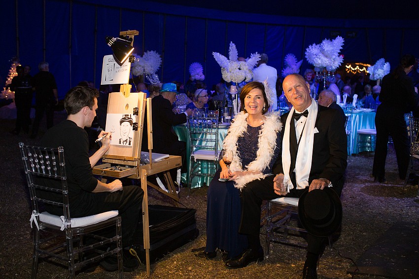 Katy Barclay and Denis Bicard get their caricature drawn by Michael White.