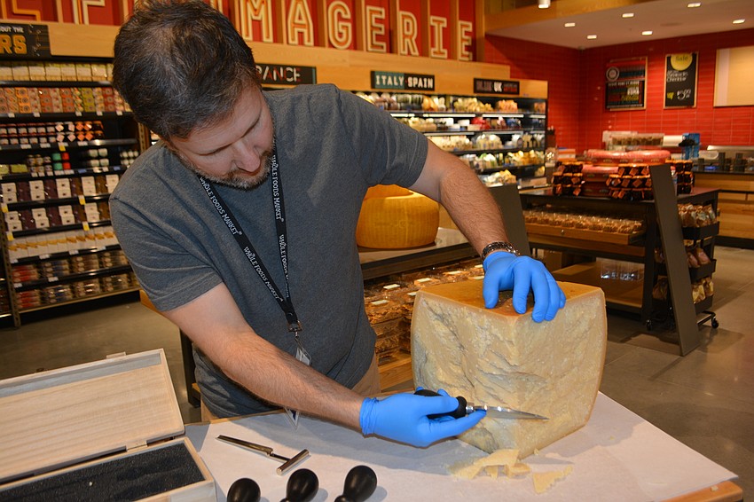 Rick Eplawy, the regional coordinator for specialty foods, cuts a piece of Parmesan Reggiano.  A code on each block allows the store to trace it back all the way to the cow.