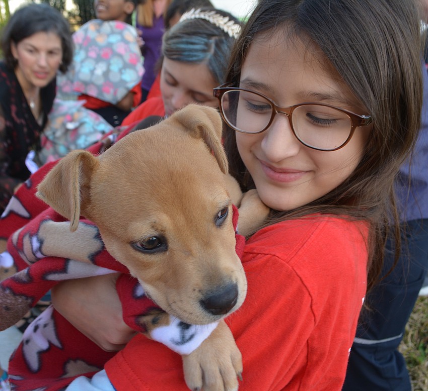 Tylee Giorgio wraps a puppy in a blanket made by Girls Inc.