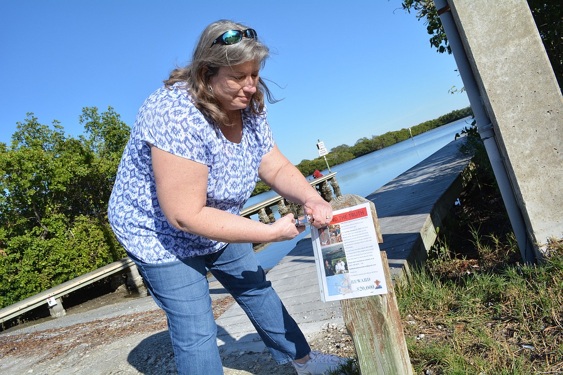 Jill Mullins attaches a flyer about the death of her husband, Patrick, to a post at the State Road 64 Boat Ramp.