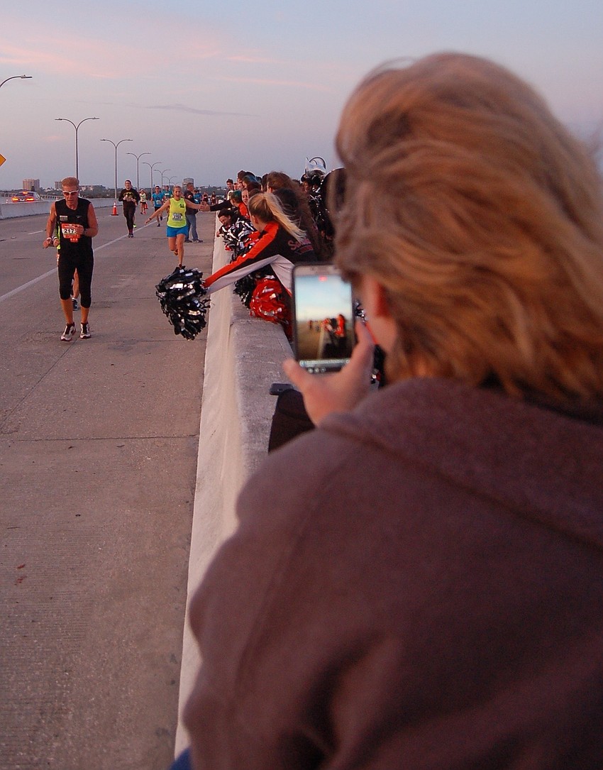 Dorothy Dekmar, a Sarasota High booster, used her smartphone to record runners interacting with the school's marching band and cheerleaders.