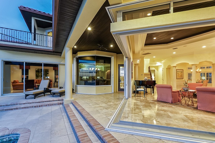 It features sliding glass doors in the living room that disappear into solid walls and connect to an outdoor sitting area.