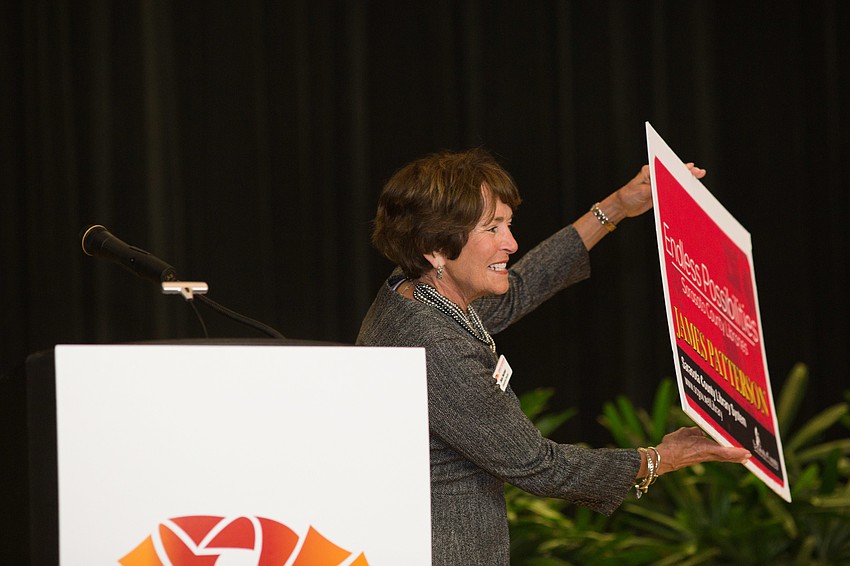 Executive Director Sue Seiter holds up a library card for James Patterson.
