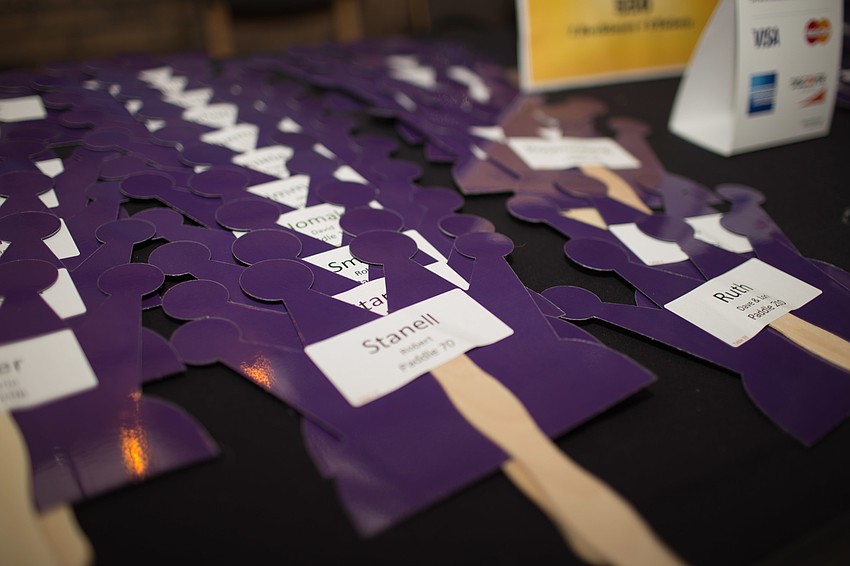 The paddles for the auction, which were shaped like a jester hat,  had the guest's name and table number on them.
