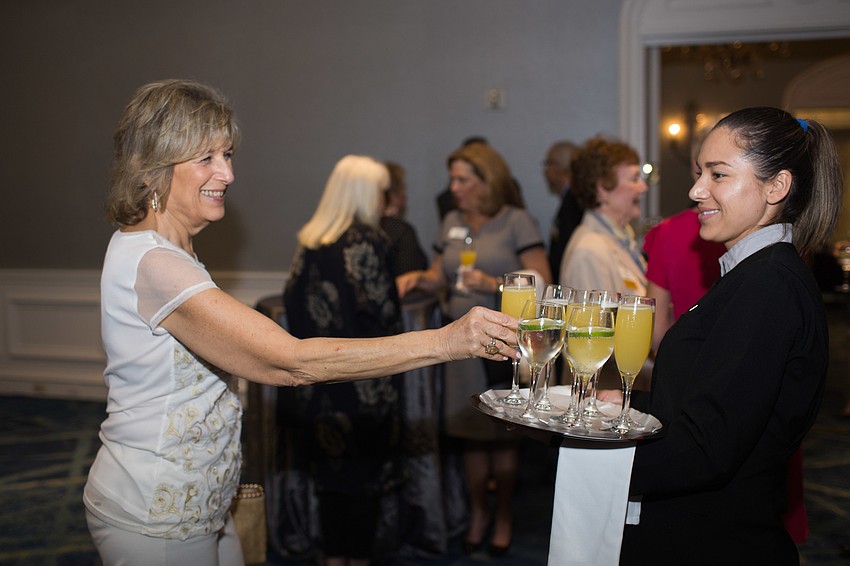 Carol Masio grabs a mimosa off the drink tray. Mimosas, champagne and cucumber water was being served to VIPs.