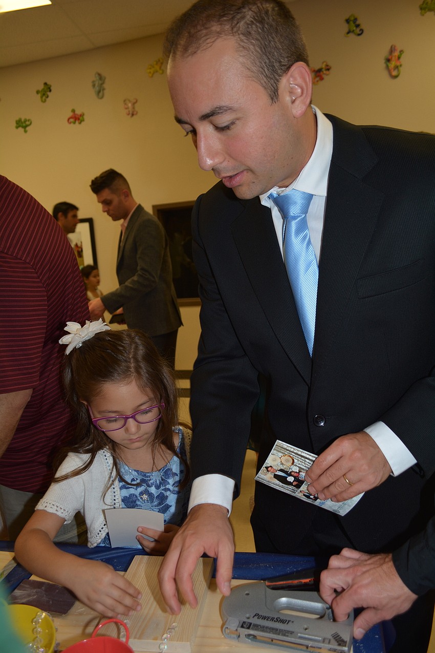 Gaston Gonzalez helps his daughter Emelia, 6, with creating a picture frame.