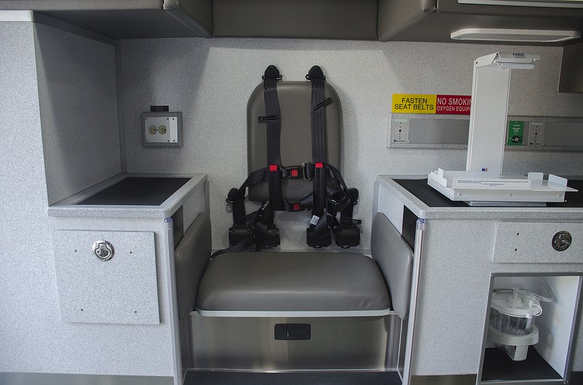 A white heart monitor mount is fixed to a cabinet top, designed to keep the device from moving around the cabin when transporting a patient.