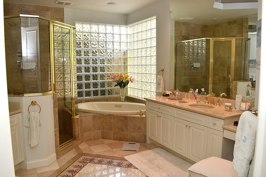Blush and gold accents fill the master bathroom that has a walk-in shower and bathtub.