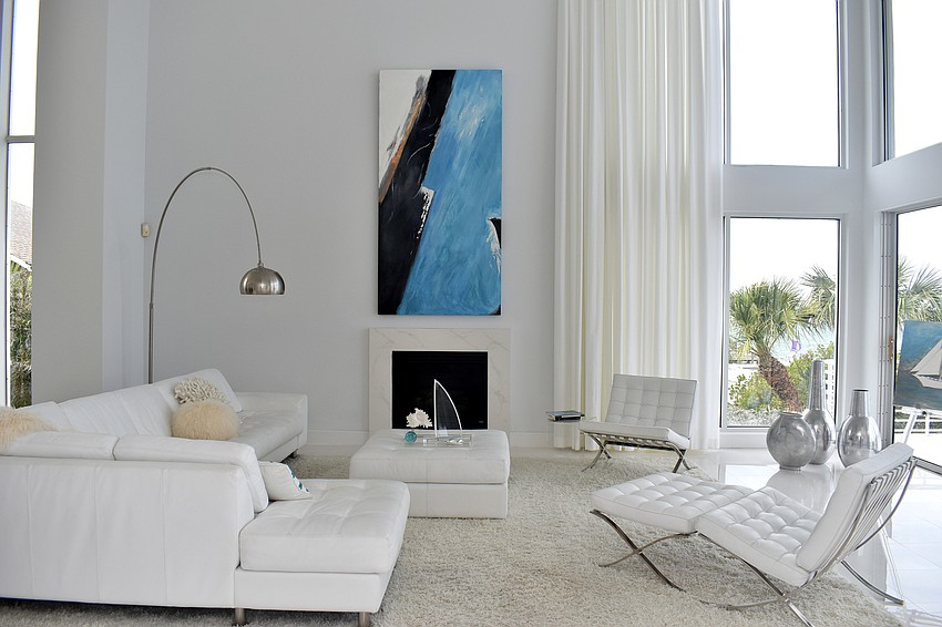 On the second floor, an all-white living room is accented with a blue abstract painting by Lila Gerich.