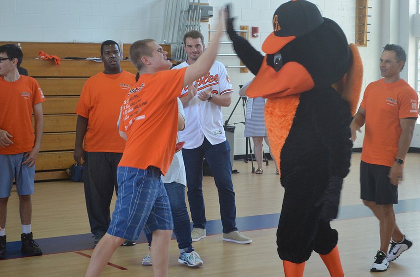 Oak Park School student Aaron Howell gives a high-five to The Oriole Bird during a special workout with the Orioles Friday.
