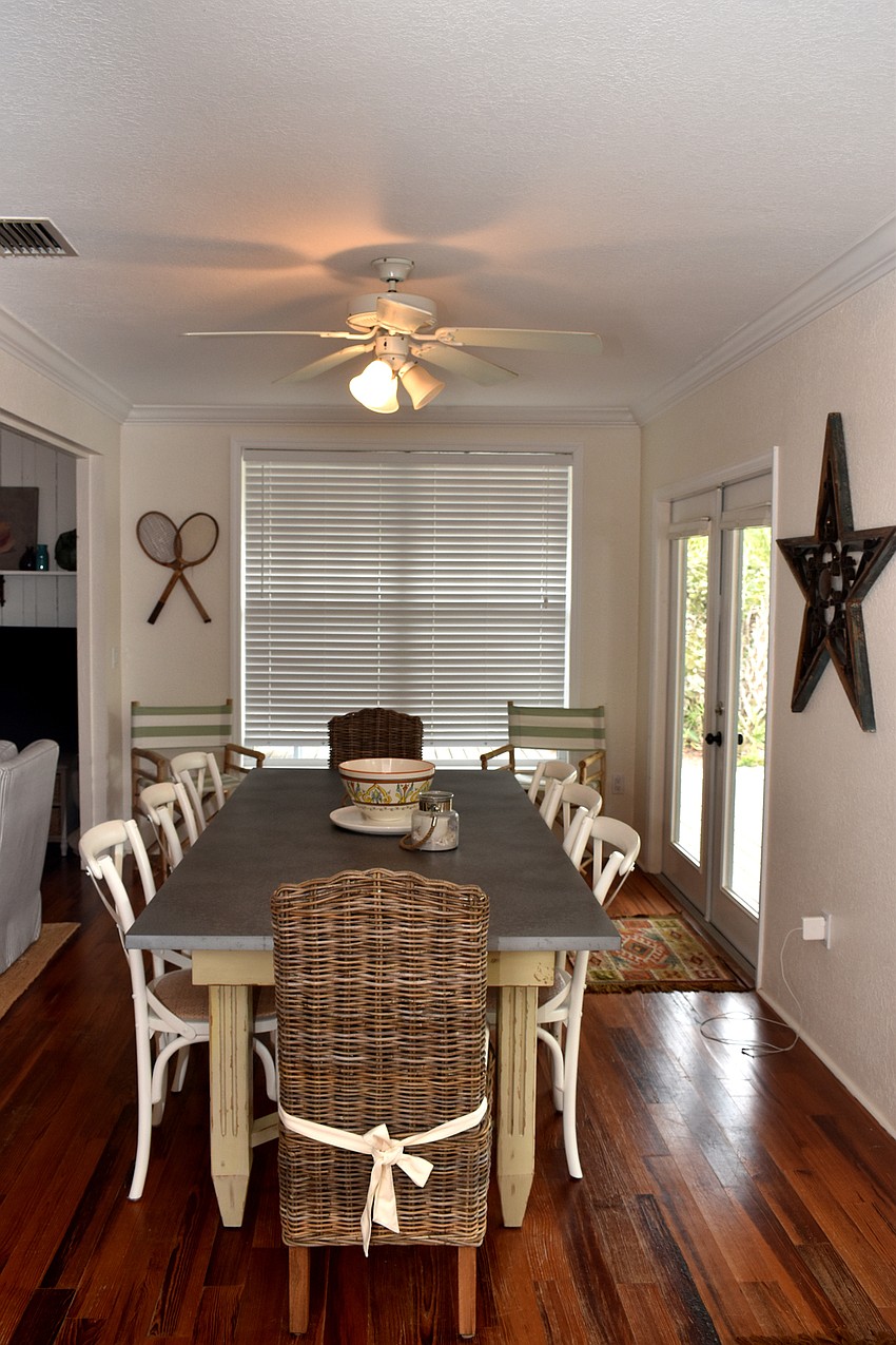 Off of a living room, a large table sits near French doors that lead out to a patio.