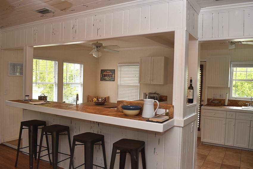 A kitchen is located to the left of the entrance with counter seating and a table in the corner.