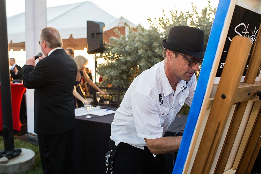 Stuart Bailey puts the finishing touches on his painting before Michael Klauber starts the bidding.