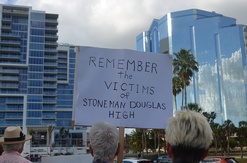 A sign held aloft during the protest encourages drivers to remember the victims of the shooting.