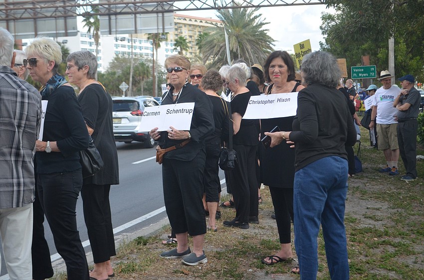 Carol Cooke (left) and Carol Hartz hold up posters to memorialize two of the victims from the shootings.