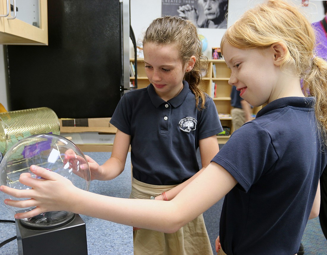 Sophie Yturralde and Caitlin Abrams examine contained currents to see what electricity looks like using a plasma globe designed by Nikola Tesla.