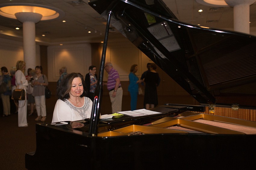 Diana Harrington plays the piano while guests enjoy the wine hour.