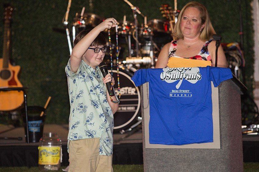 Tyler shows his beads to the crowd; each bead symbolizes a chemo treatment, bad day, good day and more from his time at the hospital.