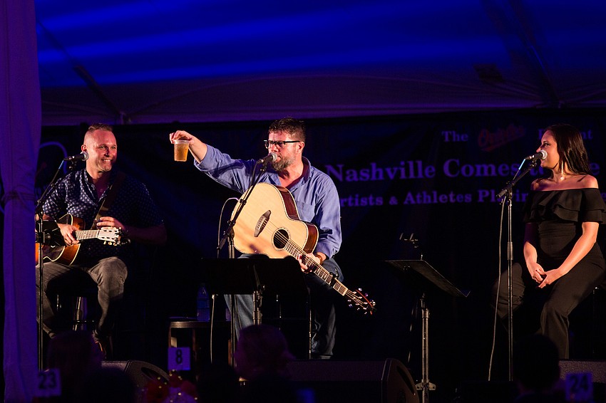Lee Thomas Miller holds up a full glass of whiskey given to him.