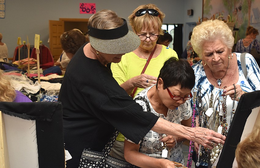 Customers peruse the jewelry table, which was one of the busiest tables of the sale.